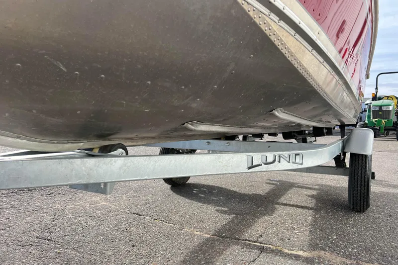 Slide: The Image of 2023 Lund SSV-14 Tiller boat on trailer, showcasing red hull and sturdy frame. - 35