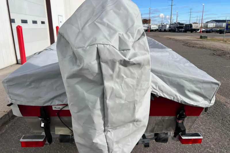 Slide: The Image of 2023 Lund SSV-14 Tiller boat covered, parked among other boats in a storage area. - 37