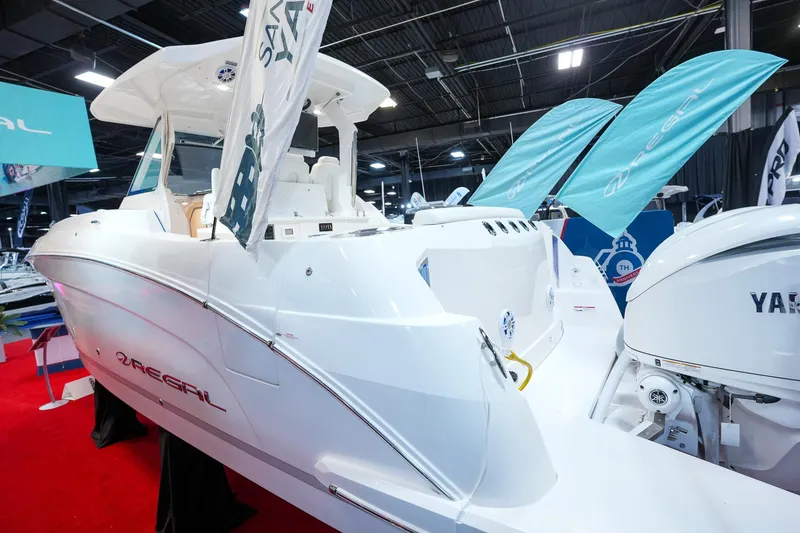 Slide: The Image of 2025 Regal 33 SAV boat displayed indoors with vibrant red carpet and promotional banners. - 3
