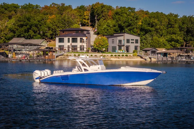 The Image of 2017 Midnight Express 39S Cuddy boat on a serene lake with waterfront homes. - 2