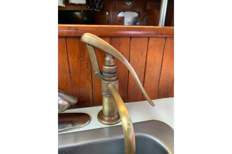 Slide: The Image of Vintage brass pump faucet on a 1981 Hardin 45 sailboat, wooden panel background. - 13