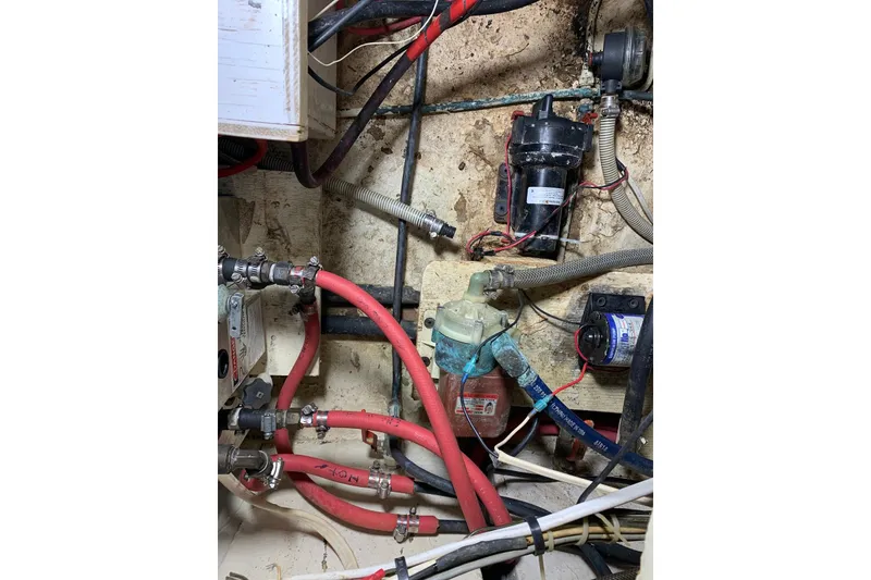 Slide: The Image of Electrical and plumbing system inside a 1981 Hardin 45 boat, featuring red hoses and wiring. - 19