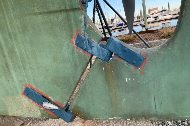Slide: The Image of Close-up of a 1981 Hardin 45 sailboat rudder with visible repairs in a marina setting. - 49
