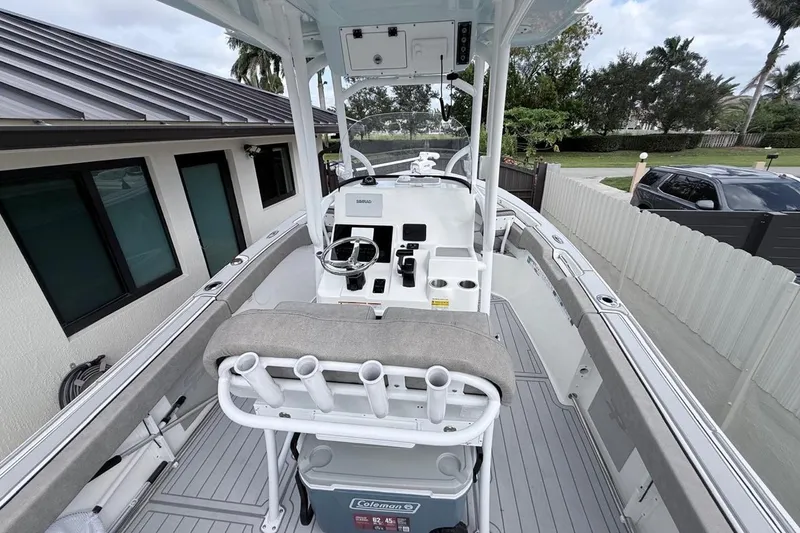 Slide: The Image of 2024 Sea Pro 222 Center Console boat with modern helm and seating, docked near a house. - 25