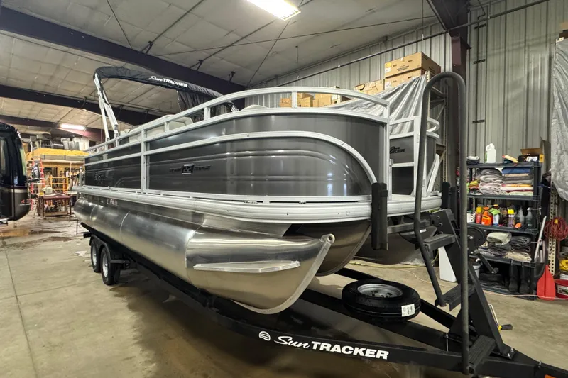 Slide: The Image of 2026 Sun Tracker SportFish 22 XP3 pontoon boat in a warehouse setting. - 2