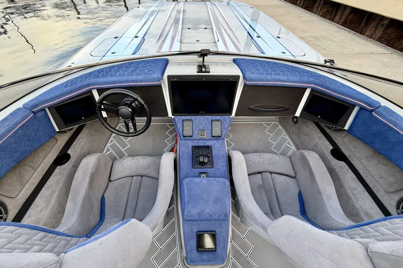 Slide: The Image of 2024 Dug Wright 32 boat interior with blue and gray seating, modern dashboard, and steering wheel. - 16