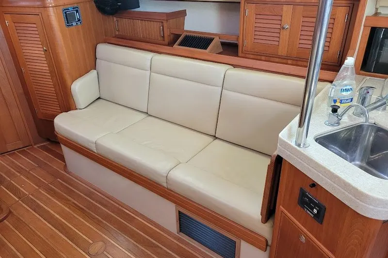 Slide: The Image of 2008 Island Packet 370 interior with beige sofa, wooden cabinetry, and compact kitchen area. - 45