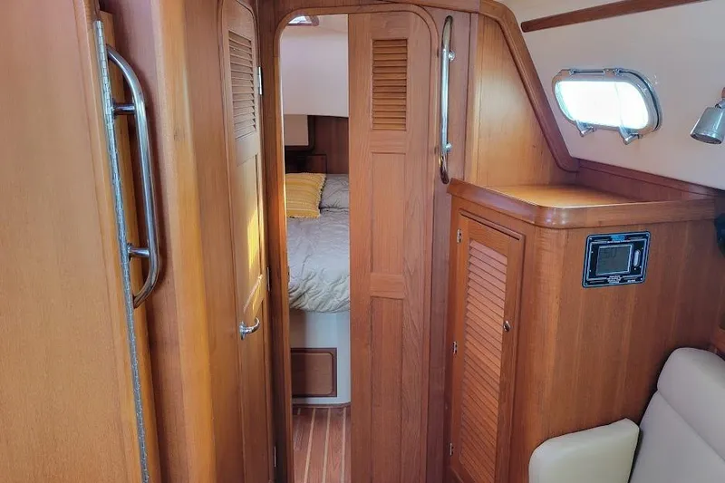 Slide: The Image of Interior of 2008 Island Packet 370 sailboat with wooden cabinetry and cozy sleeping area. - 50