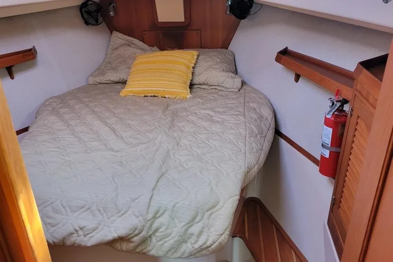 Slide: The Image of Cozy cabin interior of 2008 Island Packet 370 sailboat with bed and fire extinguisher. - 52