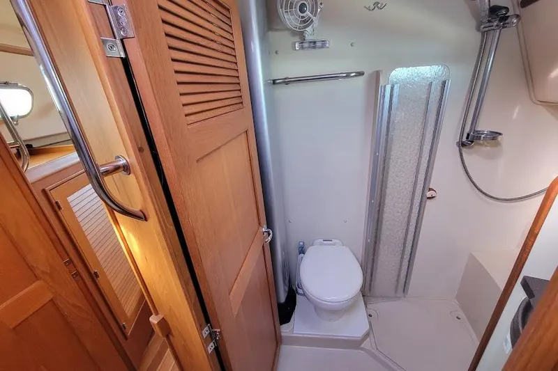 Slide: The Image of 2008 Island Packet 370 yacht bathroom with shower, toilet, and wooden door. - 63