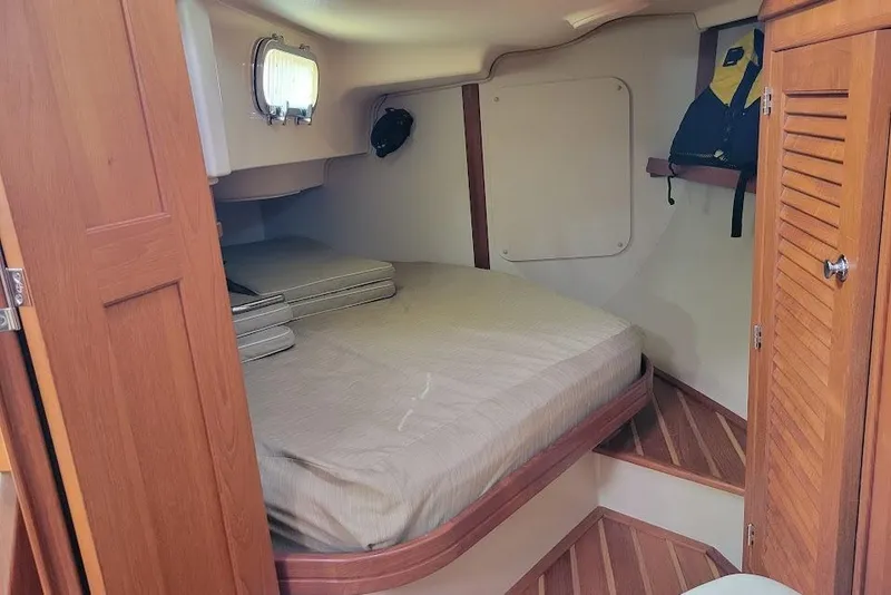 Slide: The Image of 2008 Island Packet 370 cabin interior with bed, wooden finishes, and storage space. - 71
