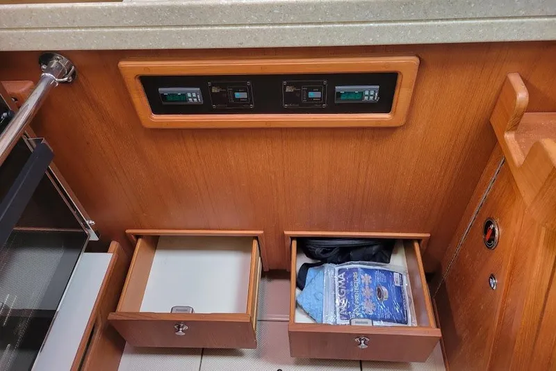 Slide: The Image of Interior of 2008 Island Packet 370 yacht with open wooden drawers and control panel. - 78