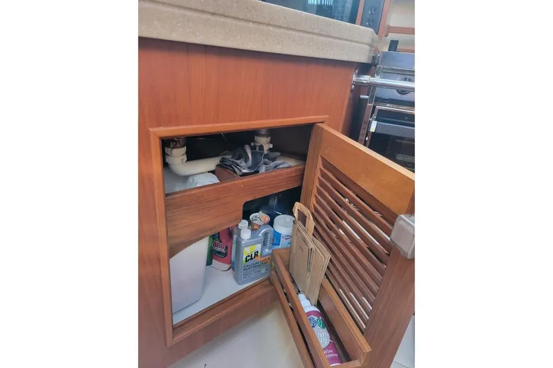 Slide: The Image of Open cabinet on 2008 Island Packet 370 yacht, showing cleaning supplies and plumbing. - 79