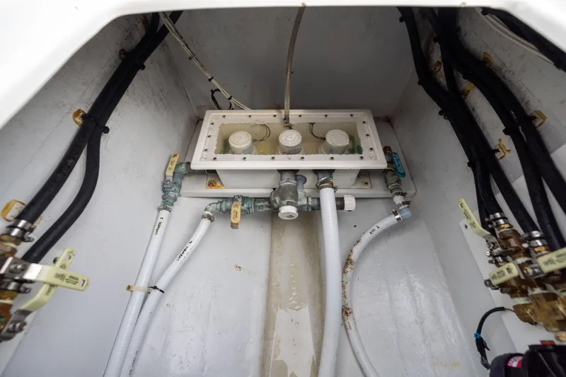 Slide: The Image of 2016 Contender 39 ST boat plumbing system with hoses and valves in a compartment. - 67