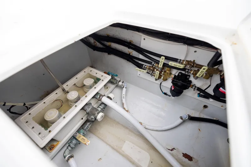 Slide: The Image of 2016 Contender 39 ST boat plumbing system with pipes and valves in a white compartment. - 68
