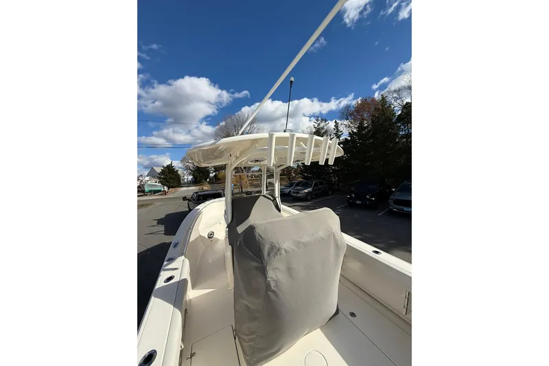 Slide: The Image of 2022 Cobia 262 Center Console boat with covered seating, parked under a clear blue sky. - 24