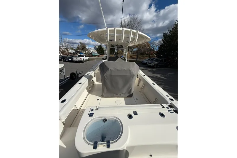Slide: The Image of 2022 Cobia 262 Center Console boat with covered seating, parked outdoors under cloudy sky. - 6