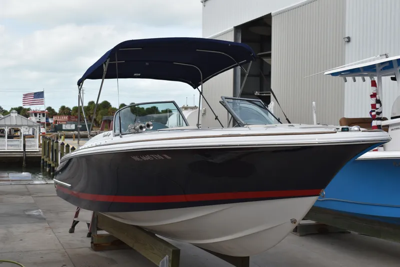 Slide: The Image of 2003 Chris-Craft Launch 25 boat docked, featuring a sleek design and navy blue canopy. - 5