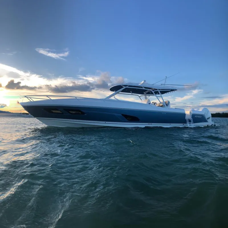 The Image of 2021 Intrepid 409 Valor boat on water at sunset, showcasing sleek design and powerful engines. - 0