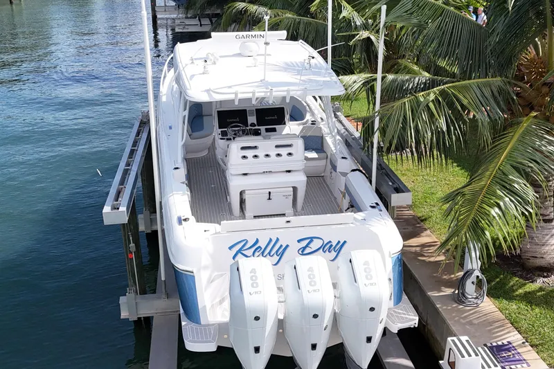 Slide: The Image of 2021 Intrepid 409 Valor boat docked, featuring triple outboard engines and lush palm surroundings. - 5