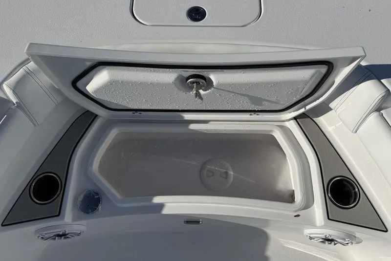 Slide: The Image of 2026 Sportsman Masters 247OE Bay Boat storage compartment with open lid and cup holders. - 9