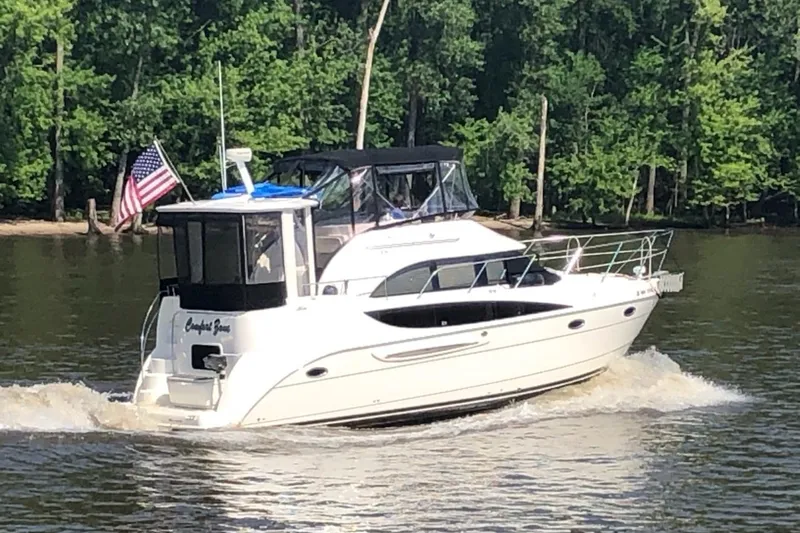 Slide: The Image of 2005 Meridian 368 Motoryacht cruising on a river with lush green trees in the background. - 2