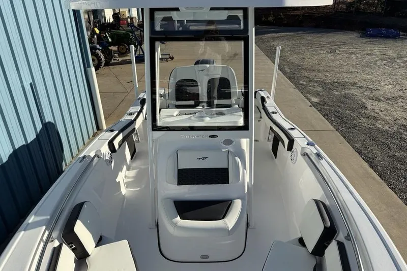 Slide: The Image of 2026 Tidewater 210 LXF boat interior with seating and console, docked near a blue building. - 6