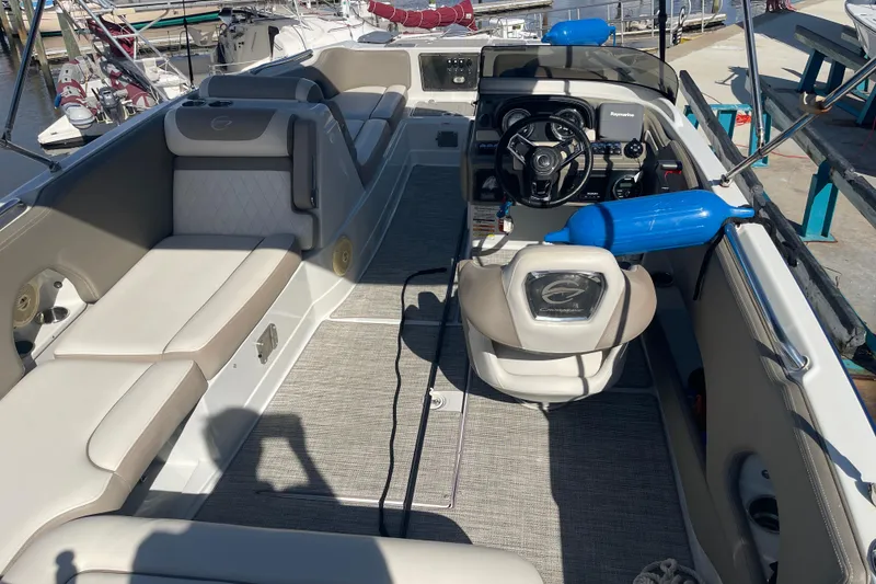 Slide: The Image of 2019 Crownline Eclipse E205 XS boat interior with seating and steering console at a marina. - 22