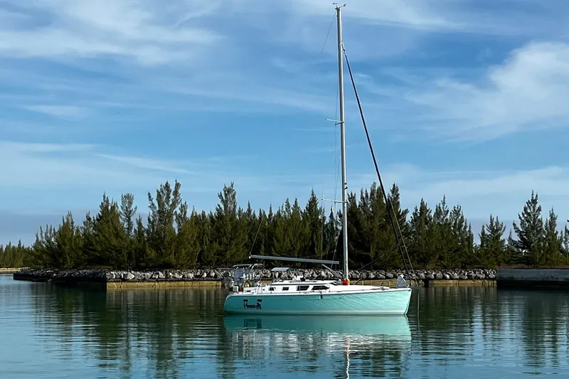 The Image of 2006 Hunter 41 Deck Salon sailboat on calm water with trees in the background. - 0