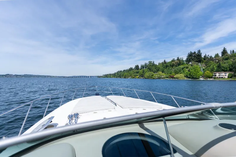 Slide: The Image of 1998 Avanti 4085 Sunbridge yacht cruising on a scenic lake under a clear blue sky. - 33