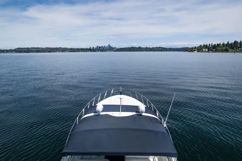 Slide: The Image of 1998 Avanti 4085 Sunbridge yacht cruising on a serene lake with city skyline. - 51