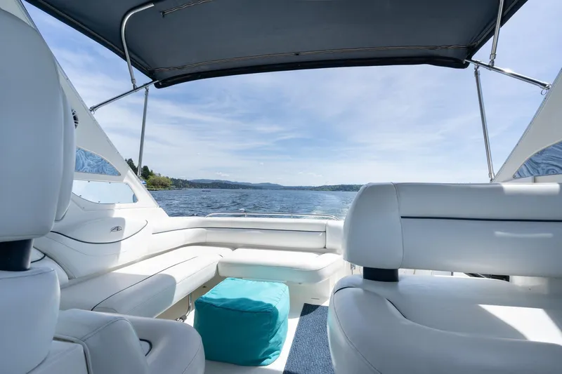 Slide: The Image of 1998 Avanti 4085 Sunbridge boat interior with white seating, blue ottoman, and scenic water view. - 8
