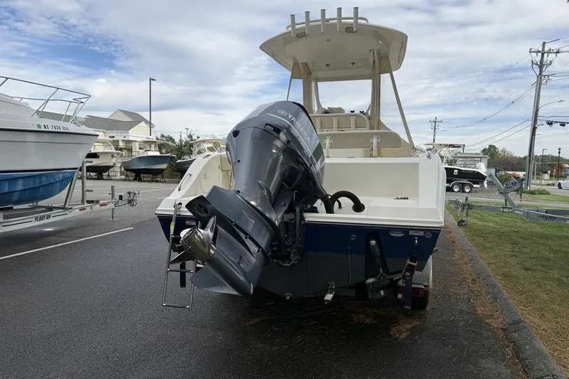 Slide: The Image of 2015 Cobia 237CC boat with outboard motor, parked on a trailer in a marina. - 4