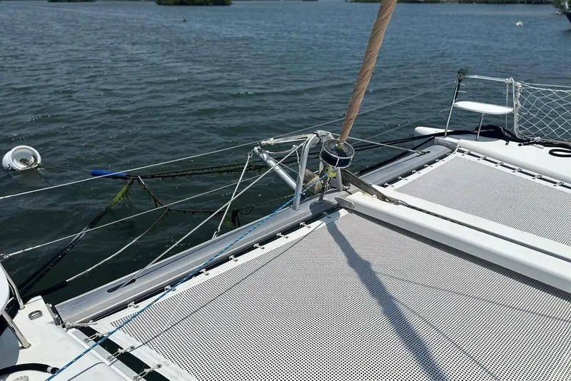 Slide: The Image of 2015 Lagoon 380 S2 catamaran deck with netting on calm water. - 30