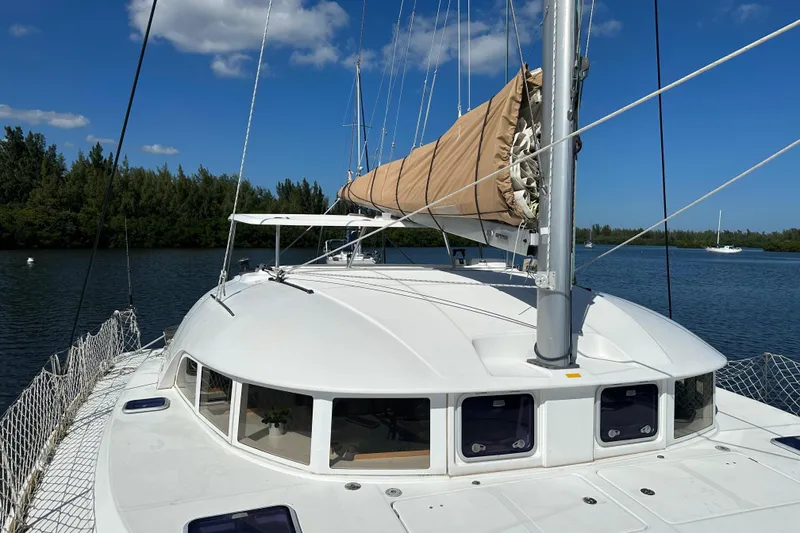 Slide: The Image of 2015 Lagoon 380 S2 catamaran on calm water, clear sky, lush greenery in background. - 31