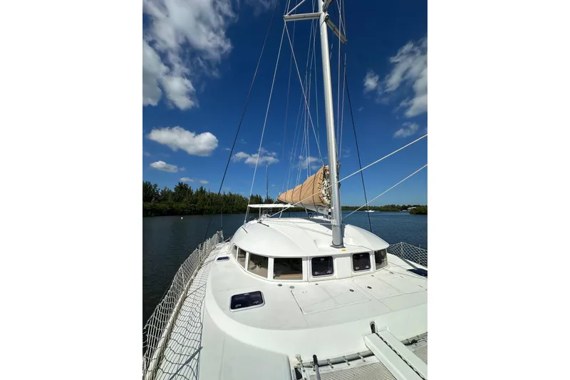 Slide: The Image of 2015 Lagoon 380 S2 catamaran sailing on a calm river under a clear blue sky. - 32