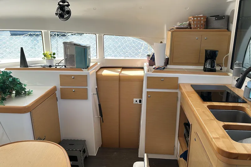 Slide: The Image of Interior of 2015 Lagoon 380 S2 catamaran kitchen with modern appliances and wooden cabinetry. - 6
