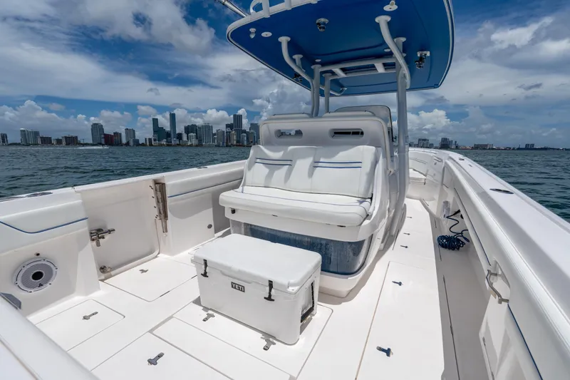 Slide: The Image of 2021 Intrepid 345 Nomad FE boat with city skyline, white seating, and cooler on deck. - 21