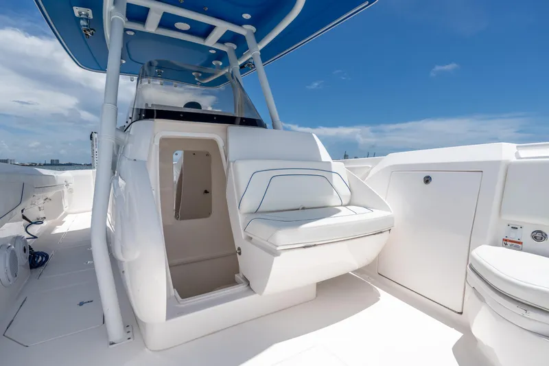 Slide: The Image of 2021 Intrepid 345 Nomad FE boat interior with seating and storage under a blue sky. - 43