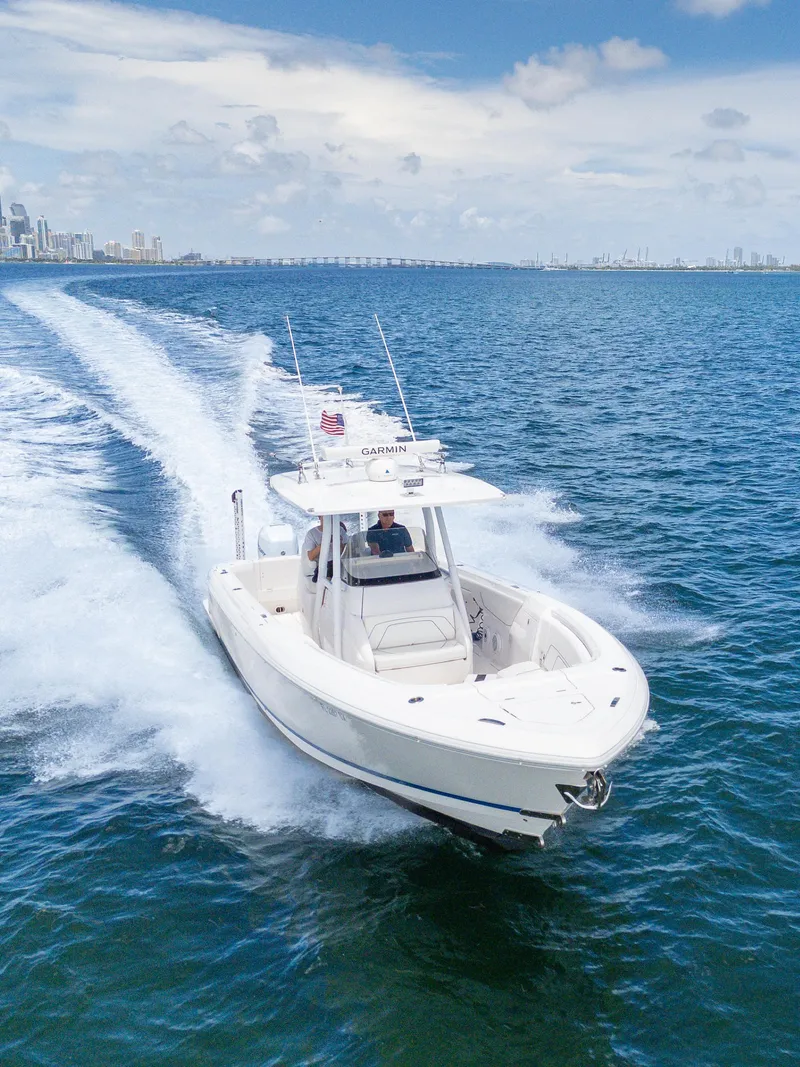 Slide: The Image of 2021 Intrepid 345 Nomad FE boat cruising on open water, city skyline in background. - 5