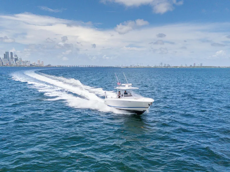 Slide: The Image of 2021 Intrepid 345 Nomad FE cruising on open water with city skyline in background. - 6
