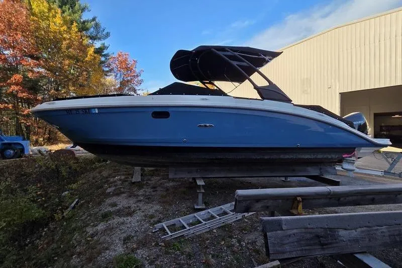 The Image of 2024 Sea Ray 270 Sundeck boat with blue hull, covered and docked outdoors. - 0
