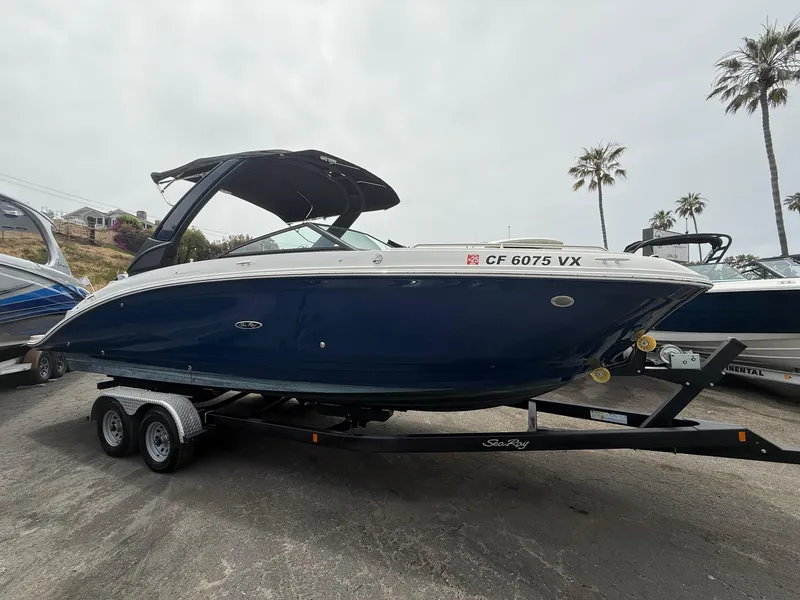 The Image of 2024 Sea Ray SDX 270 Outboard boat on trailer, parked outdoors with palm trees. - 0