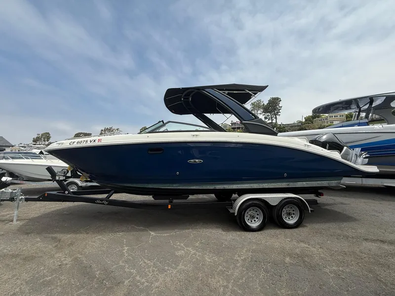 Slide: The Image of 2024 Sea Ray SDX 270 Outboard boat on trailer, side view, blue hull, parked outdoors. - 3