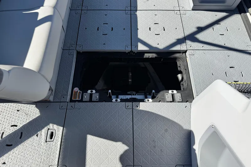 Slide: The Image of 2023 Sea-Doo Switch Cruise 21 deck with open storage compartment, gray seating, and textured flooring. - 12