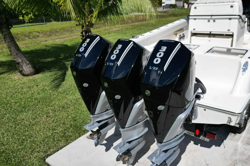 Slide: The Image of 2024 SeaVee 340Z boat with triple 300 V8 Mercury outboard engines, parked on grass. - 4