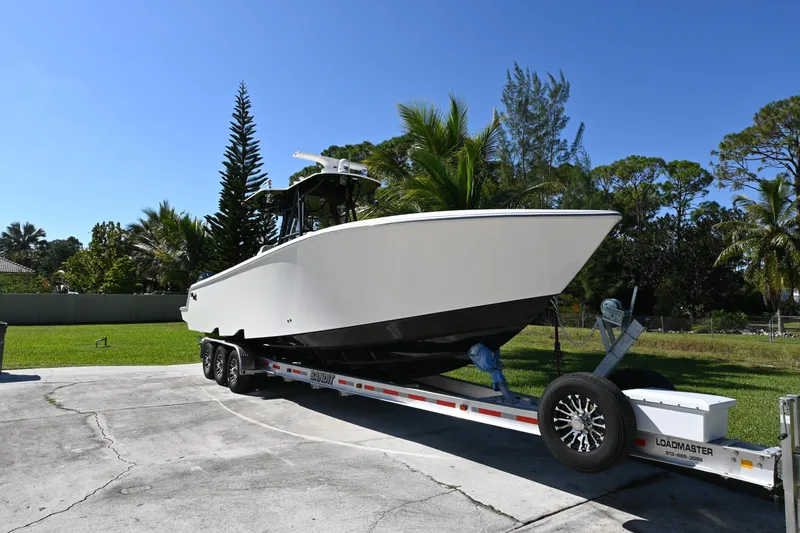 Slide: The Image of 2024 SeaVee 340Z boat on trailer, parked outdoors with lush greenery background. - 5