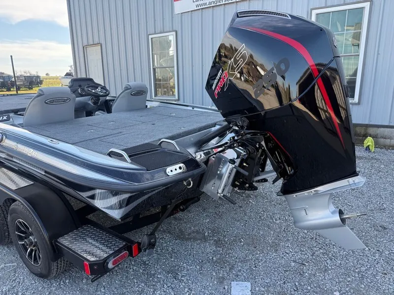 Slide: The Image of 2026 Phoenix 721 ZXL boat with powerful outboard motor, parked on gravel near a building. - 9