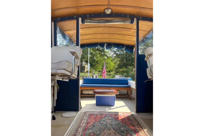 Slide: The Image of 1988 Cape Dory Hardtop interior with seating, rug, and American flag in view. - 15