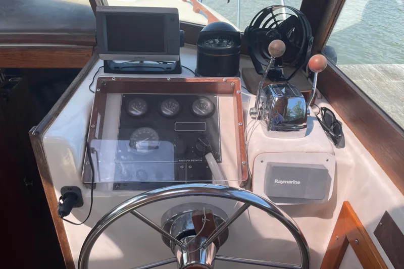 Slide: The Image of 1988 Cape Dory Hardtop boat dashboard with steering wheel, gauges, and navigation equipment. - 17